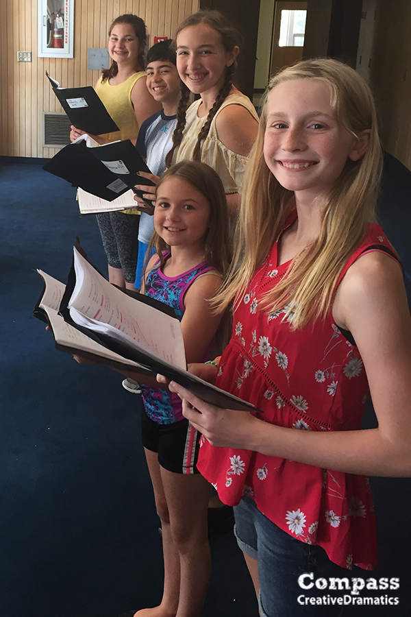A group of theatre campers read from their scripts as they rehearse for a production of 